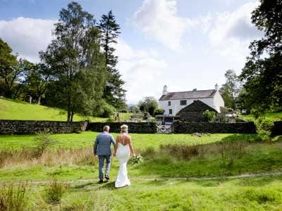 A bride and groom walking back from the lake to the wedding reception at Cote How in Rydal