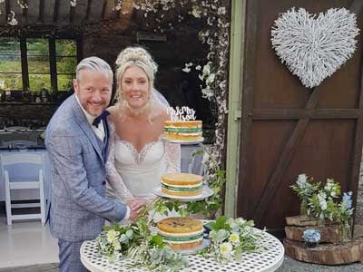 Bride and Groom cutting the wedding cake outside the rustic barn at Cote How
