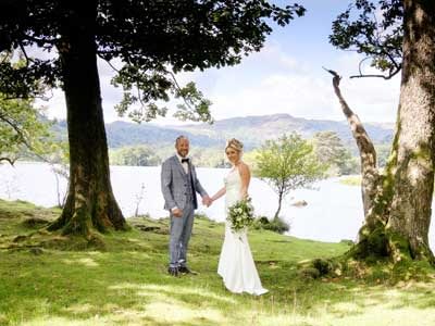 Bride and Groom hand in hand on the lake shores of Rydal Water after having their legal wedding ceremony at Cote How in Rydal