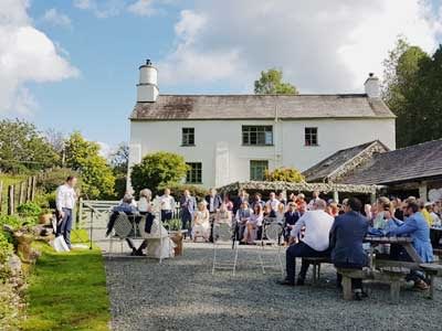 Evening Wedding Reception as guests sit around for the speeches Al Fresco in the evening sunshine outside the barn