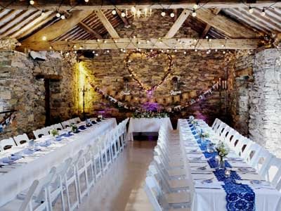 Tables dressed in white linen with blue lace for the Wedding Breakfast Set up in the ancient barn at Cote How