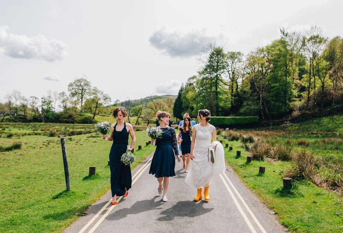 Bride in yellow wellies walking to her own wedding
