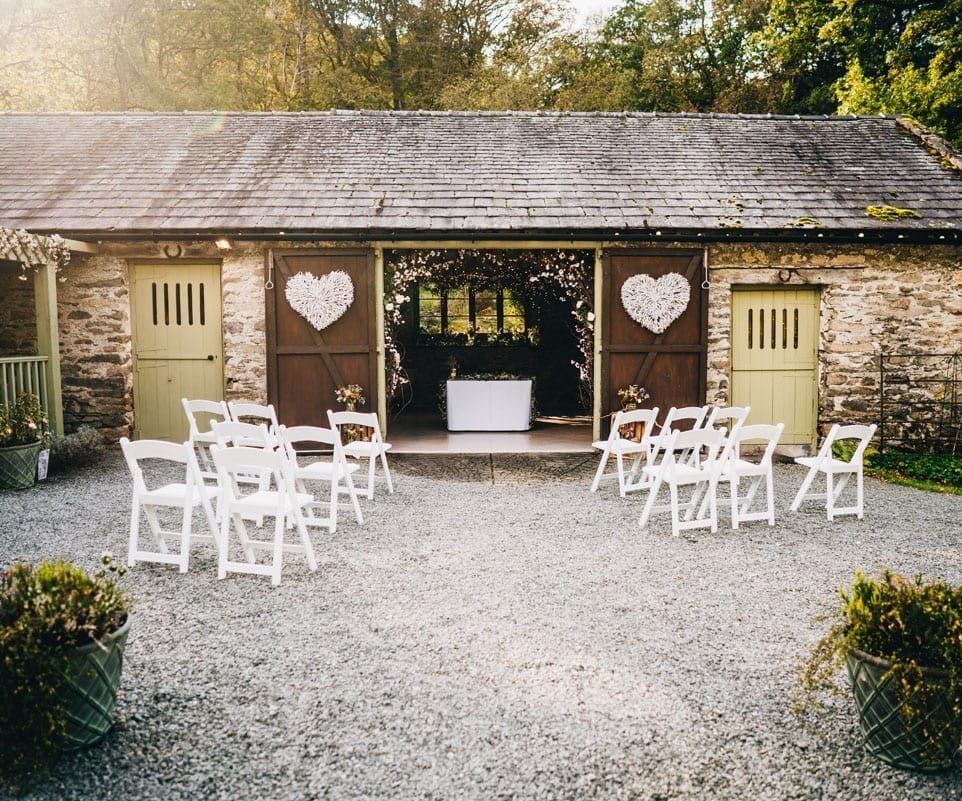 Outdoor Lake District Barn Wedding Ceremony set up with white chairs