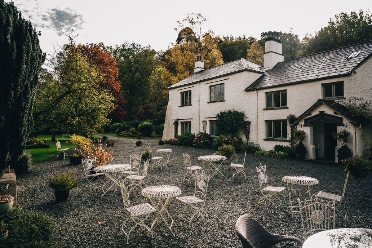 White Lake District Farmhouse Wedding Venue with outdoor wrought iron tables and chairs for drinks reception