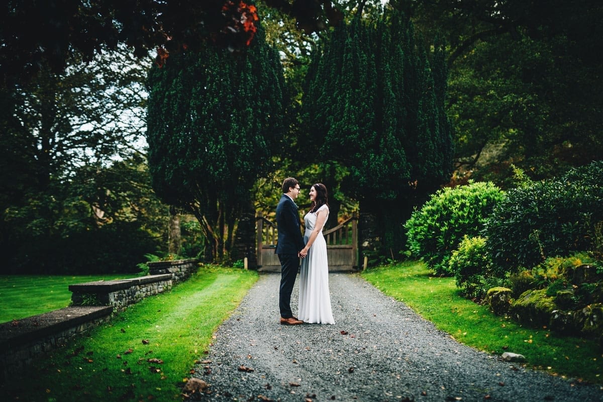 Bride and Groom with yew trees behind them in the driveway of Cote How in the Lakes after their Covid wedding in 2020
