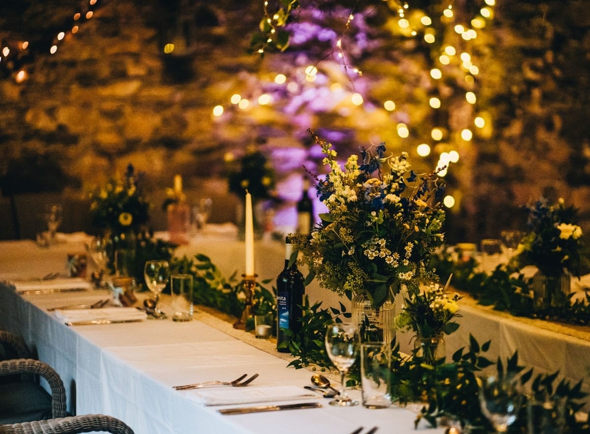 Table Setting in a wedding barn with warm glowing candlelight and fairy light tablescape