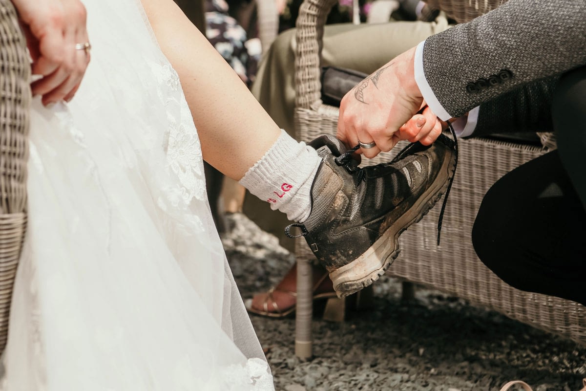 Groom helping bride with her walking boots