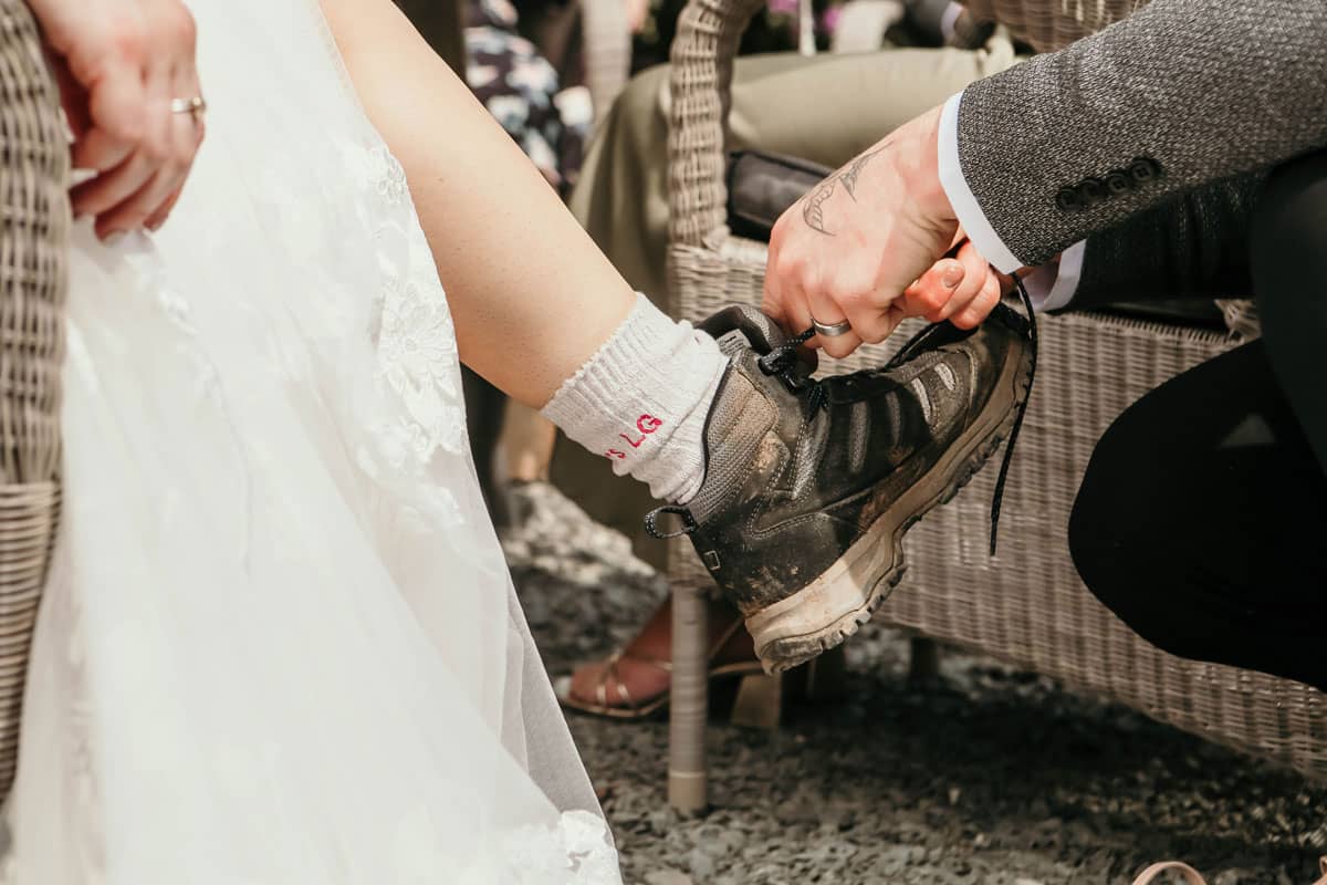 Groom helping bride with her walking boots