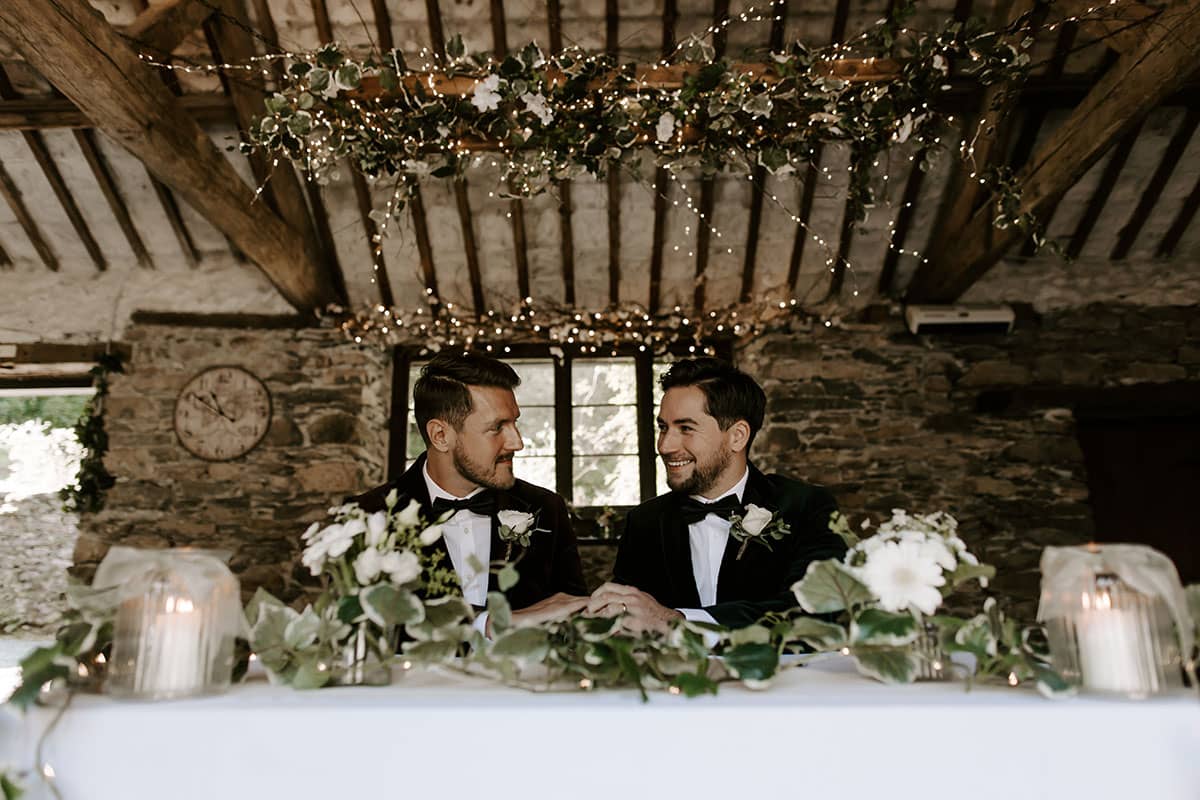 Gay wedding couple sat inside the barn for their ceremony signing