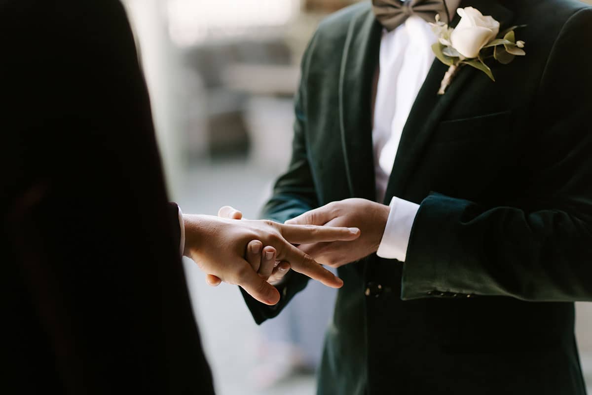 Gay couple enchanging wedding rings during their elopement ceremony